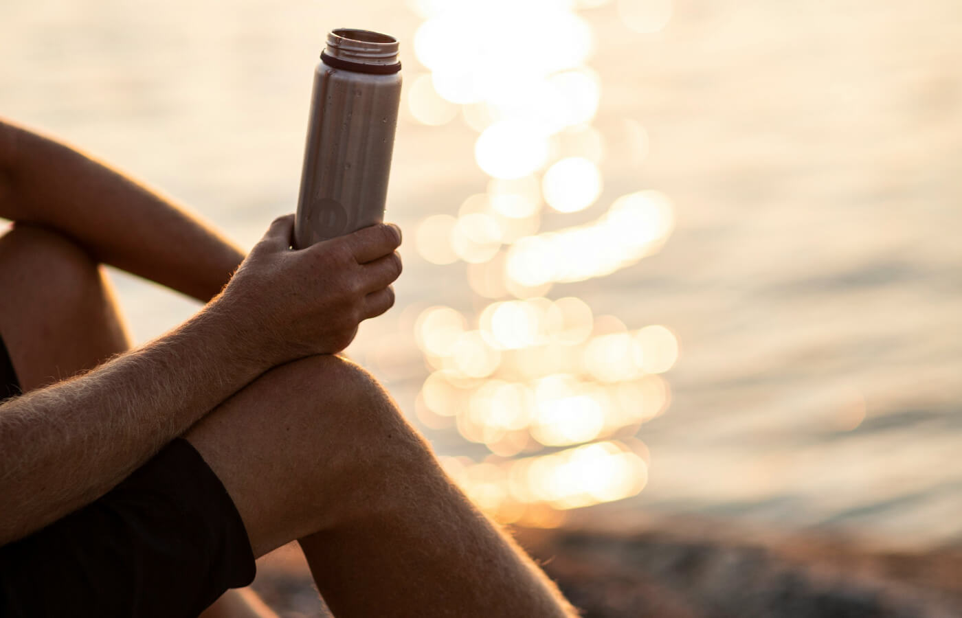 man holding water bottle at beach