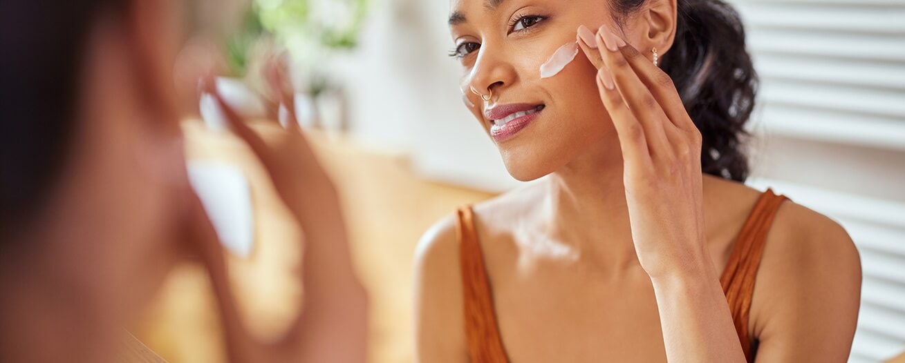 Woman applying lotion to her face