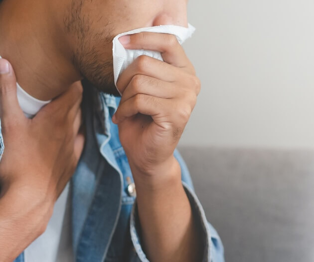 Person sneezing with tissue