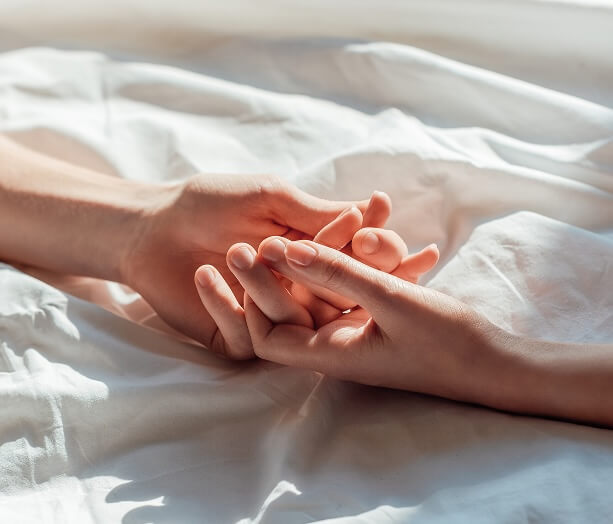 Partners holding hands in bed