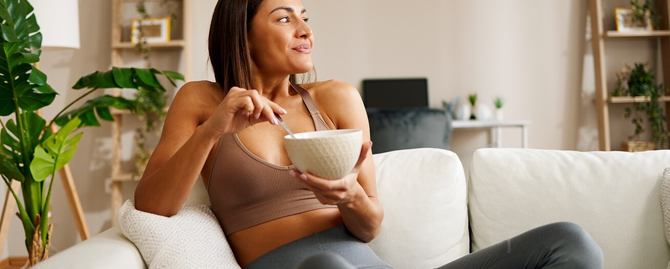 woman sitting on couch eating out of bowl